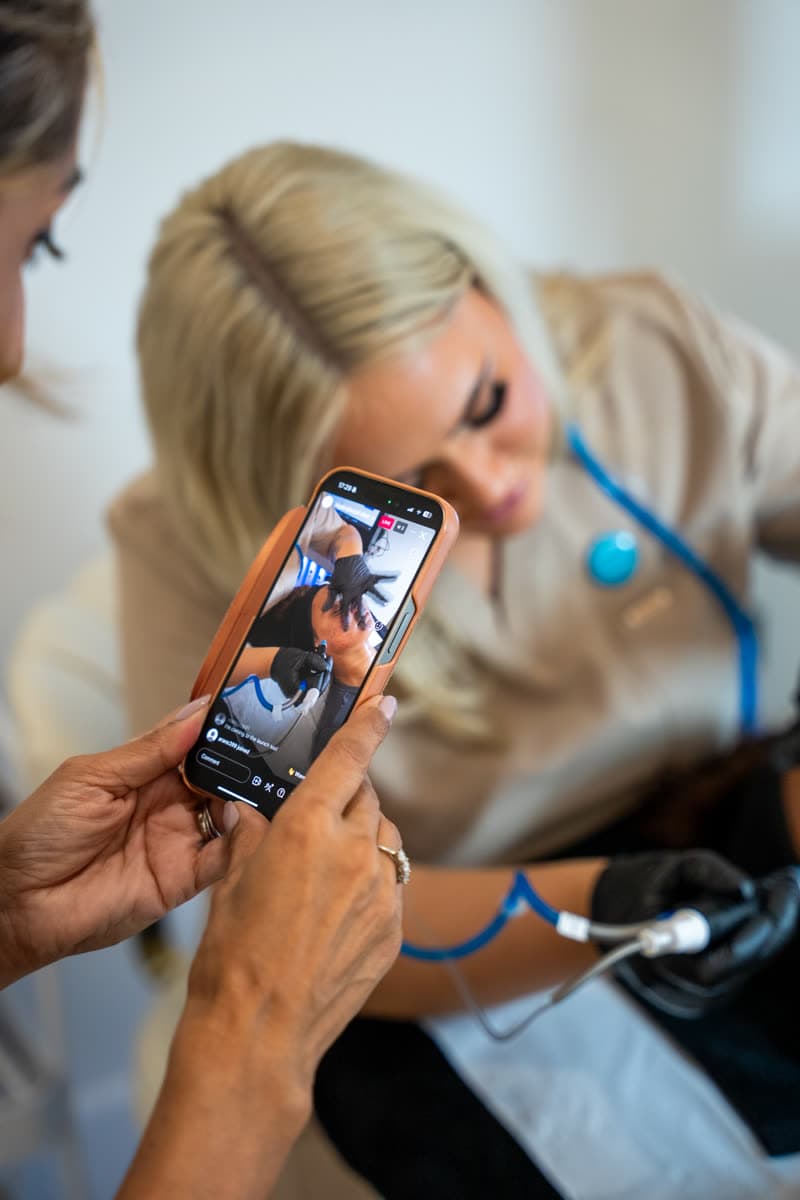 A practitioner reviewing session footage during a treatment at Empress Skin