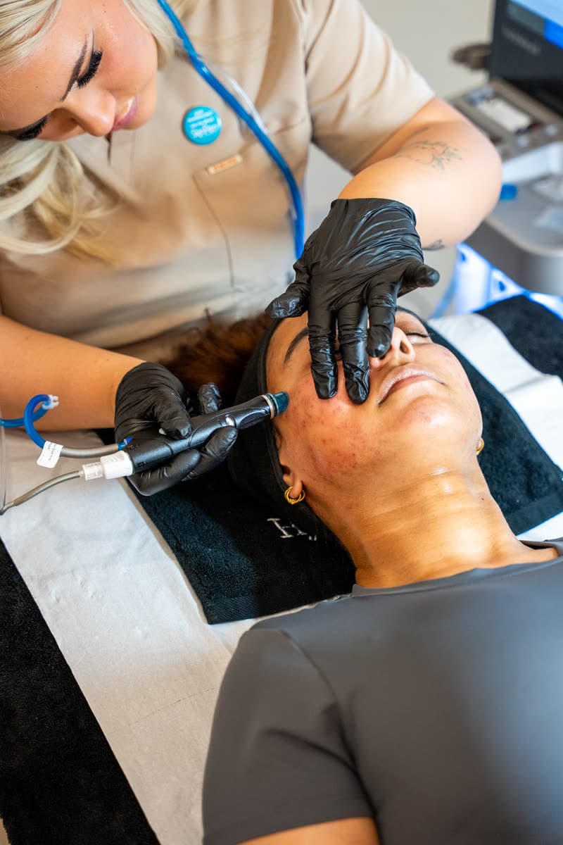 A practitioner carrying out a Hydrafacial Syndeo treatment